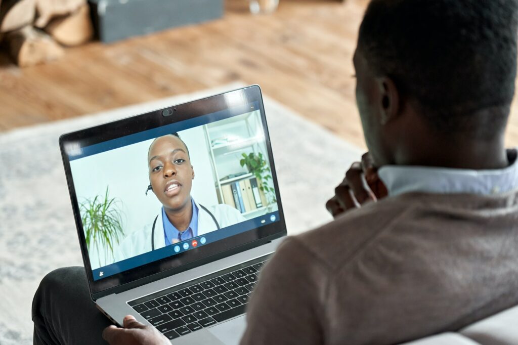 Male black patient on conference video call with female african doctor.